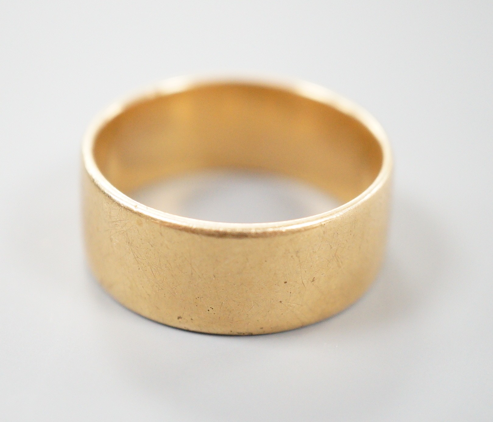 A yellow metal wedding band, unmarked, size P, 7.4 grams.